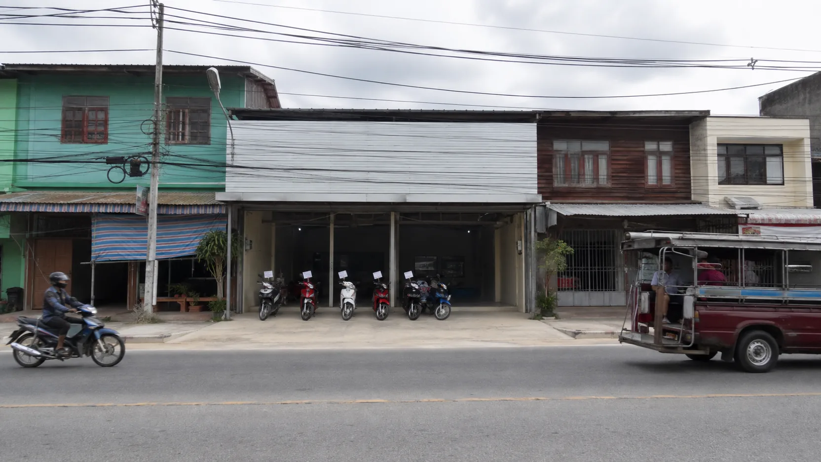 The Rungrueang Motor shop front on a market road in Roi Et, motorcycles parked out front, a plain sign.